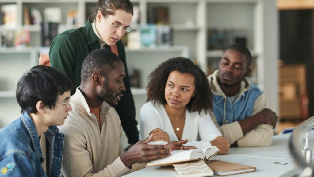 A group of college students sitting together at a table, studying and talking, showing a supportive space for autism in college