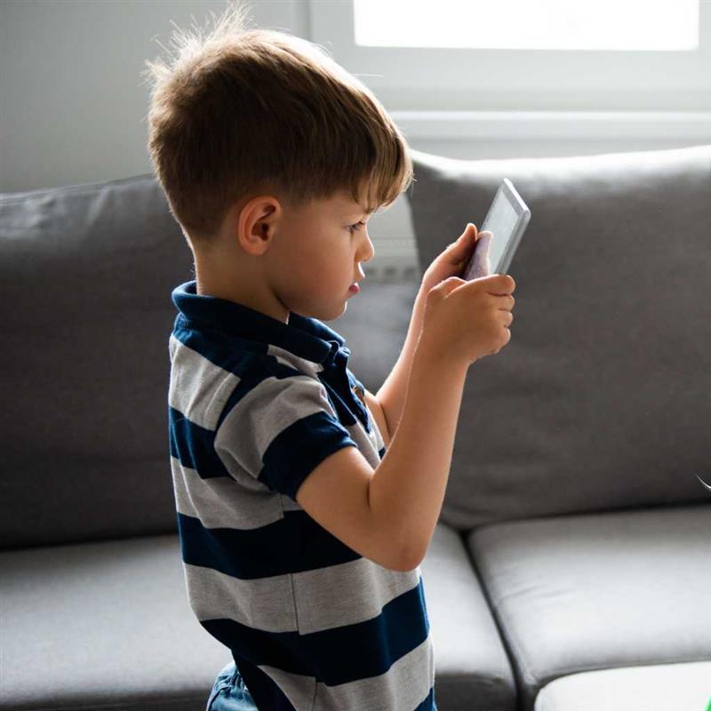 Young boy using a communication device to express himself, representing augmentative and alternative communication for nonverbal autism.