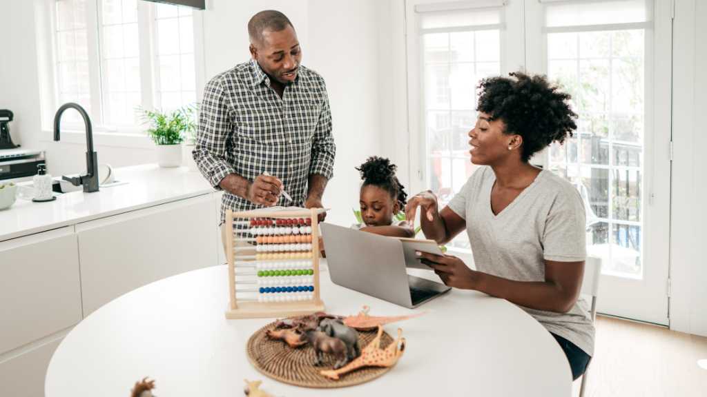 Autism and Finances: A Practical Guide to Financial Planning for Families in Virginia Parents reviewing finances on a laptop at home while supporting a child, illustrating autism and finances in Virginia and available family supports.