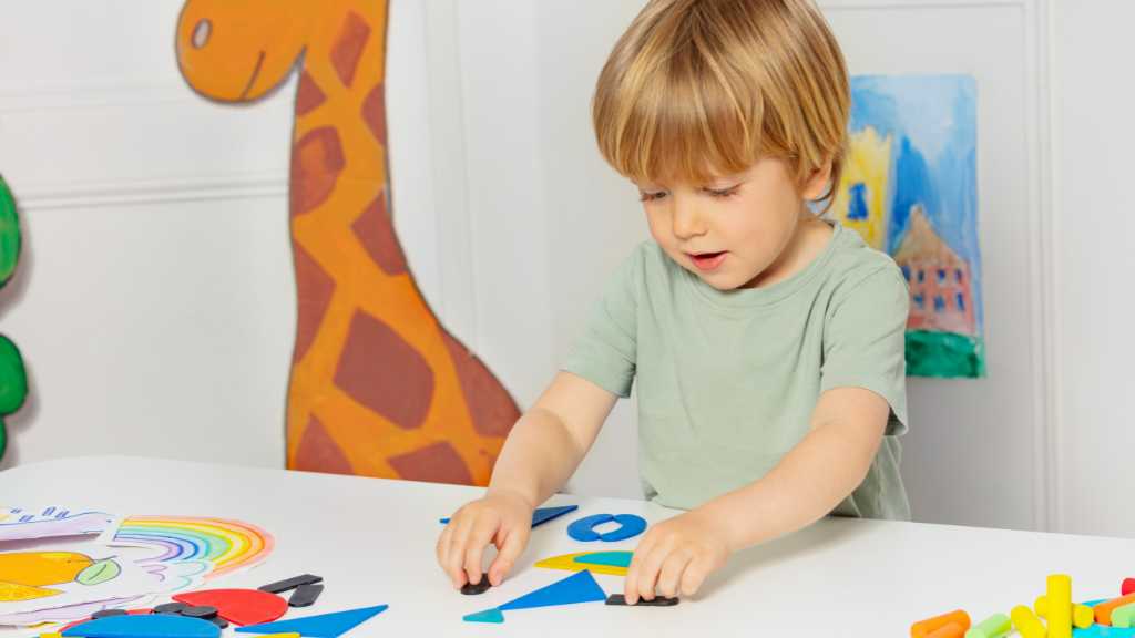 Young child playing with shapes at a table, illustrating the shift from types of autism to levels of autism and individual support needs
