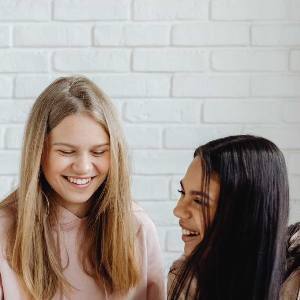 Autism in Adults: Understanding Life Beyond the Diagnosis Two women smiling and talking together, representing friendship, confidence, and connection while living with autism as an adult.