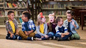 Diverse group of neurodivergent and neurotypical children sitting together in a library, symbolizing inclusion and understanding of neurodiversity concepts like neurodivergent vs neurodiverse.