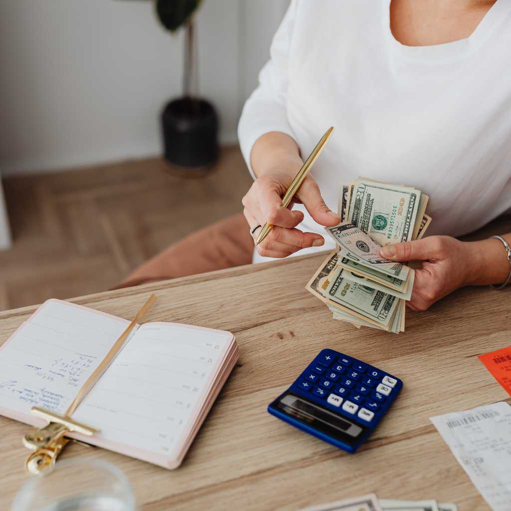 Person counting cash and reviewing expenses with a calculator, highlighting financial planning challenges for families affected by autism.