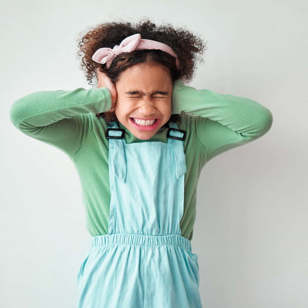 Child covering her ears in response to discomfort