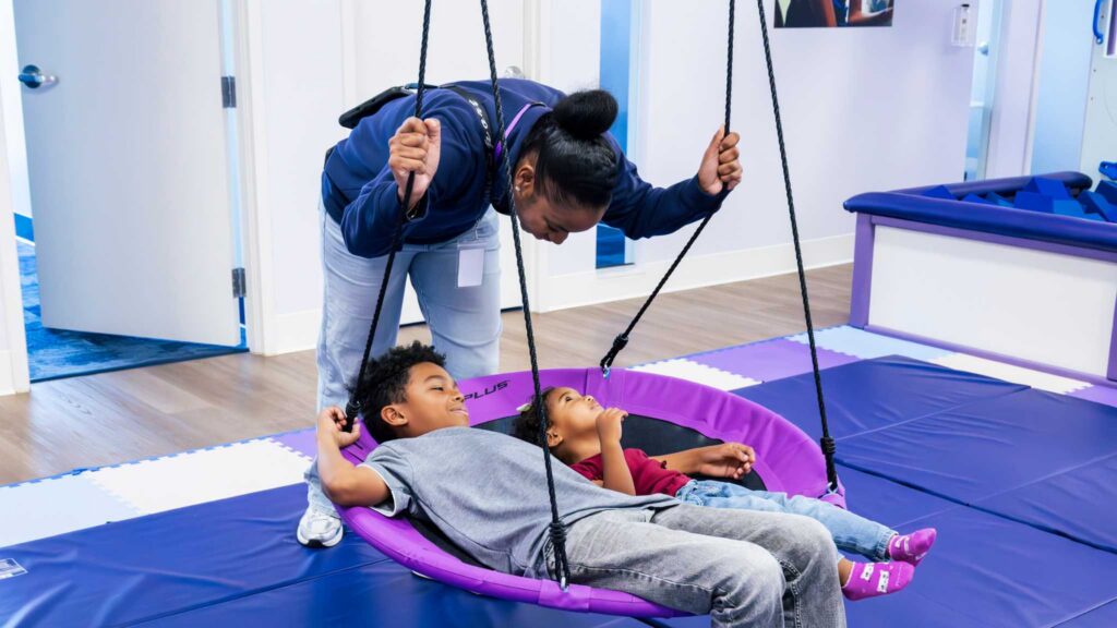 Children using sensory swing with therapist support after autism evaluation