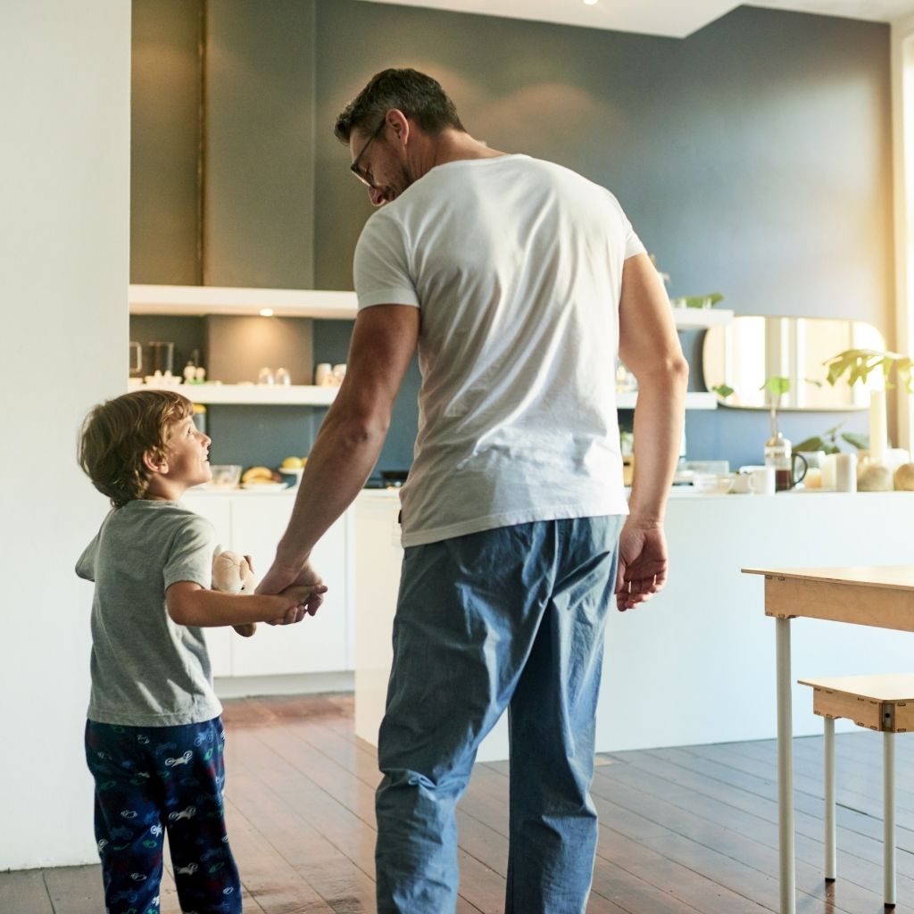 Father holding hands with his child illustrating how an autism parenting journey may look like at home