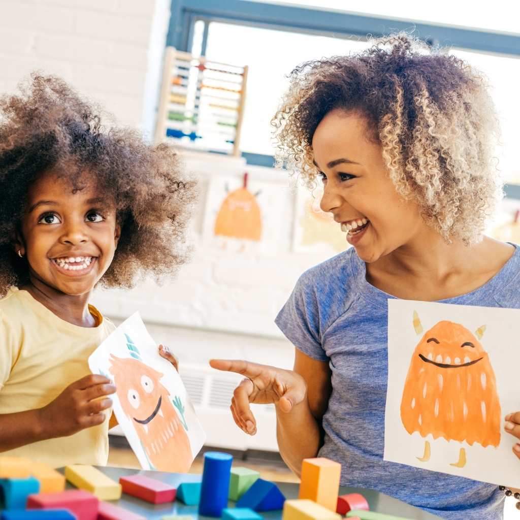 Parent and child smiling together while sharing artwork during a creative activity